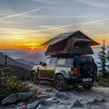 On the top of the mountain, the sunset reflects, and the roof tent becomes a camping home